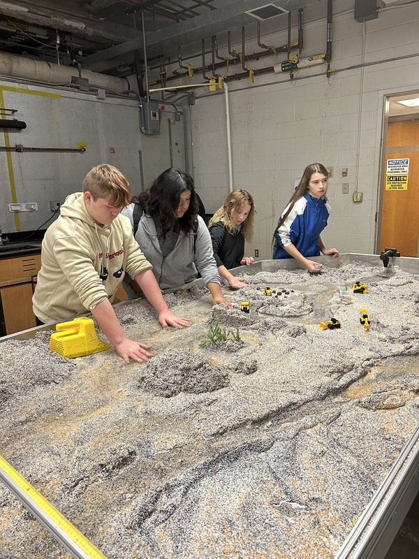 Students mark out the floor of a river on a model map.