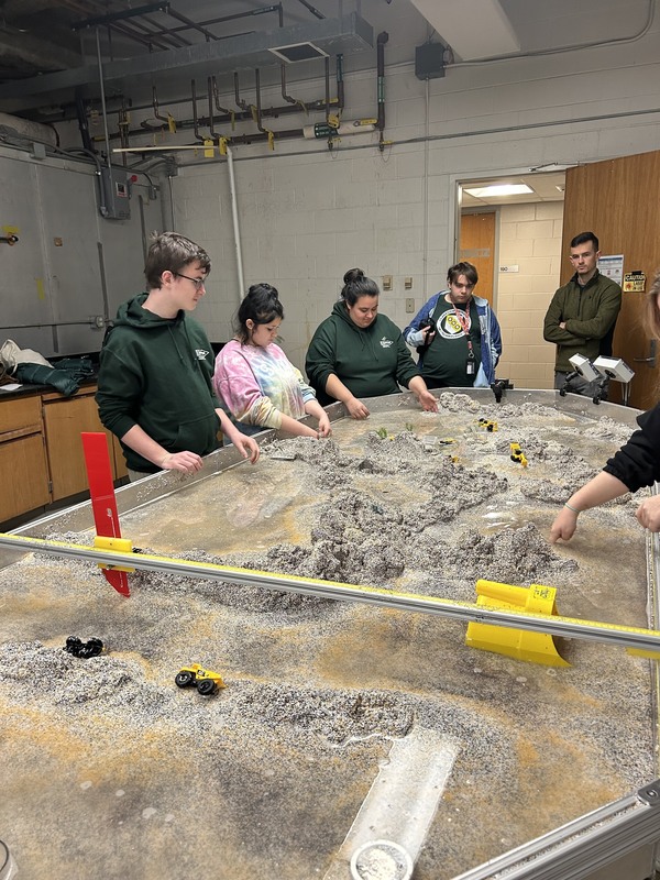 Students mark out the floor of a river on a model map.
